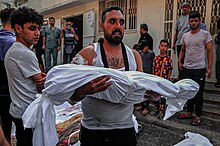 A man carries the body of a Palestinian child killed during the shelling of 17 October 2023 Fars Photo of Casualties in Gaza Strip during 2023 War 05.jpg