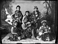 Five hula dancers with ukulele and guitar. Seated right Lizzie Puahi (PP-32-9a-023).jpg