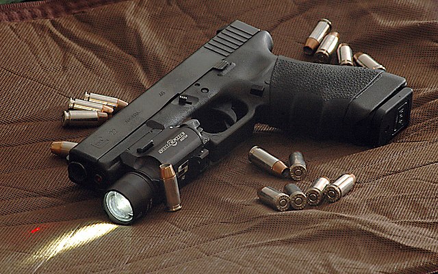 A Glock 22 semi-automatic pistol chambered in .40 S&W with a tactical light mounted below its barrel.