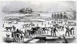 Ice harvesting at Spy Pond, Arlington, Massachusetts, 1852, showing the railroad line in the background, used to transport the ice Ice Harvesting, Massachusetts, early 1850s.jpg