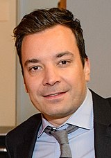 Jimmy Fallon in a suit and tie with a neutral expression