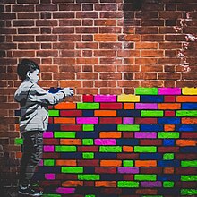 A mural by Hendog of a boy placing coloured bricks on top of eachother, creating a wall.