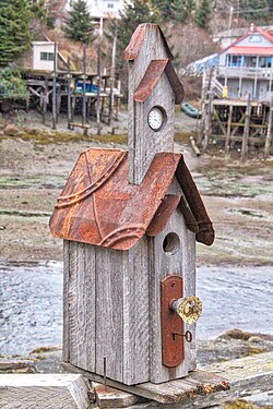 abschliessbares Vogelhaus mit Uhr in einem Küstenort an der Küste Alaskas