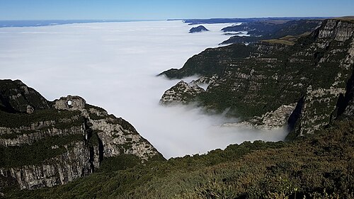 View from Morro da Igreja, in Urubici, Santa Catarina, Brazil; the São Joaquim National Park valley is covered by fog in the morning and the Pedra Furada (Drilled Stone) is visible on the left.