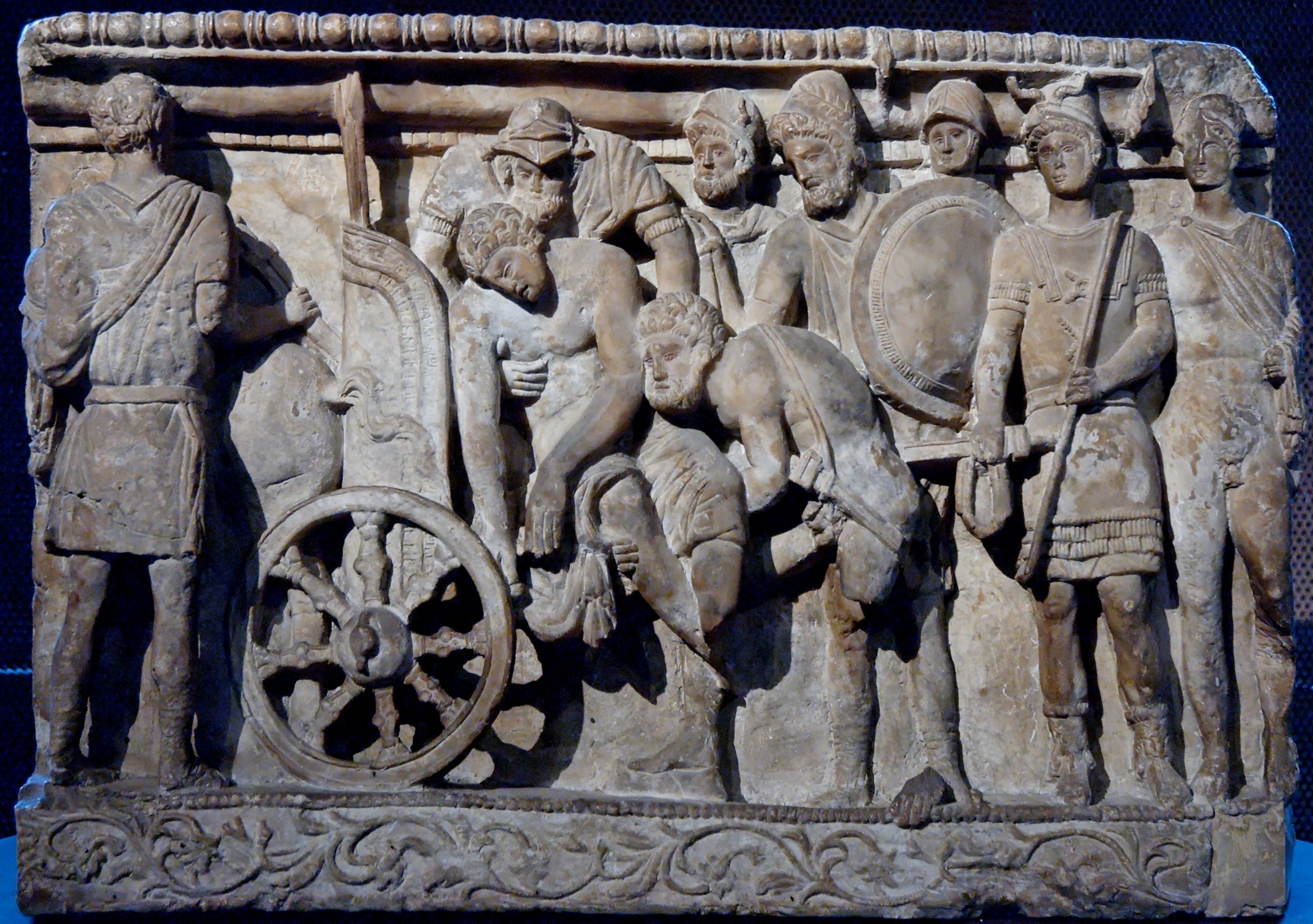 The body of Patroclus is lifted by Menelaus and Meriones while Odysseus and others look on (Etruscan relief, 2nd century BC)