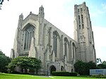 A large stone building with a carillon tower. The building has many turrets, arches, and columns.