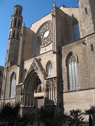 Stone façade of the Gothic Cathedral with a rose window, arched entrance, and bell tower.