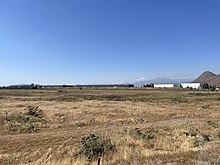 Terreno al costado de la laguna del humedal, de fondo se ven las fábricas que rodean el predio.