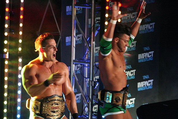 Godderz with Robbie E (right) as the TNA World Tag Team Champions in April 2014