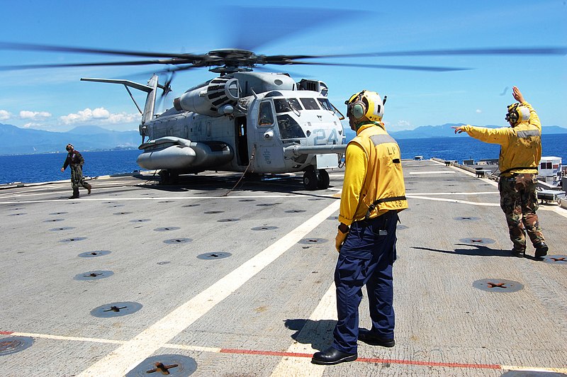 File:US Navy 091009-M-1998T-009 Airman Tione Williams and Airman Adam Pond, assigned to the amphibious transport dock ship USS Denver (LPD 9), signal Marine pilots.jpg