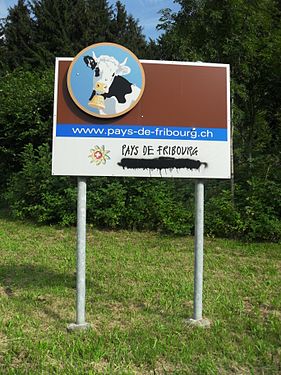 A bilingual sign that someone didn't take a liking to. This sign welcomes visitors to the bilingual Canton of Fribourg and was originally written in French ("Pays de Fribourg") and German ("Freiburgerland"). The German portion has been smeared over by vandals. The location of the sign is in the French-speaking part of the Canton, near the border to the Canton of Vaud.