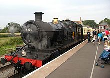 A black steam engine (number 5224) with passengers alighting at a station platform.