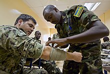 A Sudanese service member, right, applies a bandage to U.S. Navy Petty Officer 3rd Class Douglas Barton's arm during exercise Cutlass Express 2013 at the Port of Djibouti in Djibouti Nov. 13, 2013