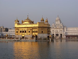 A temple in golden colour with a pool in front