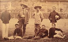 Photographie représentant sept hommes (trois Blancs, quatre Asiatiques) dont plusieurs en uniforme. Auguste Pavie, âgé d'une cinquantaine d'années, est vêtu en civil, barbu et coiffé d'un chapeau.