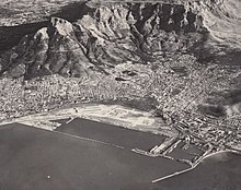 An aerial photograph of the newly completed Cape Town foreshore in 1945. Visible in this photograph as the large area of empty land between the City Centre and the newly constructed harbour out of reclaimed land from Table Bay. Cape Town foreshore 1946.jpg