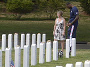 Deanie Dempsey, wife of Army Gen. Martin E. Dempsey, chairman of the Joint Chiefs of Staff, waits while LeBron James writes a note for a fallen soldier buried in Section 60 of Arlington National Cemetery, Arlington (15 July 2012)