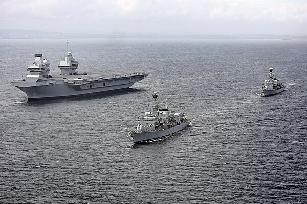 Queen Elizabeth at sea on 28 June, two days after her departure from Rosyth, in company with frigates Sutherland (foreground) and Iron Duke (backgroun