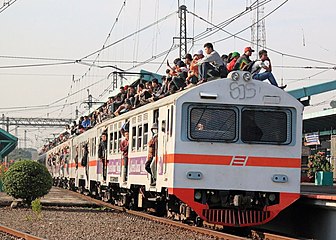 A crowded KRL Jabotabek train with passengers riding on the outside in Jakarta, Indonesia