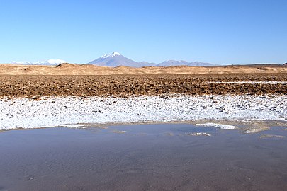 Beyaz şapkalı bir dağ ile bir gölün üzerinde yükselen arazi fotoğrafı