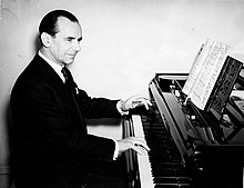 middle aged white man seated at the keyboard of a grand piano