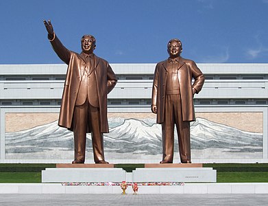 Estátua dos líderes com o museu ao fundo e o mosaico da Montanha Baekdu na parede do mesmo