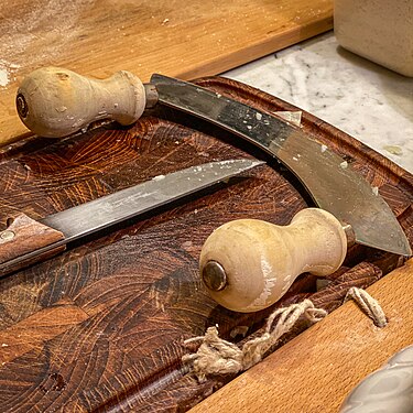 A mezzaluna and knife on a cutting board