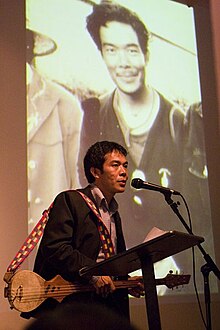 Ngawang Choephel speaking about his film (holding a Tibetan lute) Ngawang Choephel at podium w dranyen.jpg