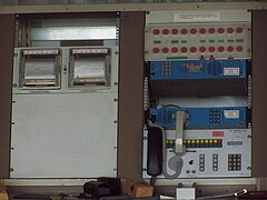 Pupitre de commande, bâtiment principal ; la rangée de boutons rouges servait à positionner les antennes en survie ; à gauche des boutons : 2 anémomètres, pour les antennes (2008). Les 2 boitiers bleus sont des téléphones Inmarsat.