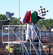 The flagman displaying the chequered flag with a complete set of stockcar racing flags