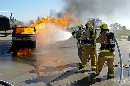 Student fire fighter extinquishing dumpster fire.jpg