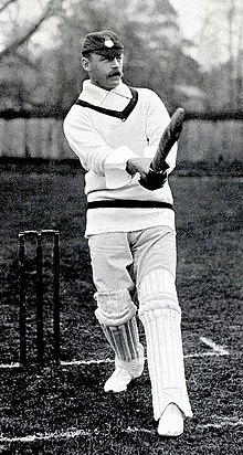 A black and white photo of a cricketer holding a cricket bat