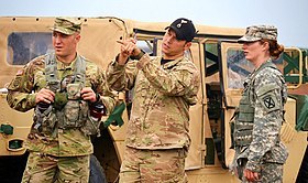 A special skills instructor, known as a "Black Hat," demonstrates a quick method to determine the height of an obstacle on a landing zone. US Army Pathfinder Instructor.jpg