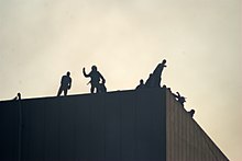 Silhouetten von Menschen auf einem Dach, die Projektile werfen.