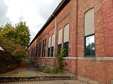 Mur d'un bâtiment en brique avec beaucoup de fenêtres.