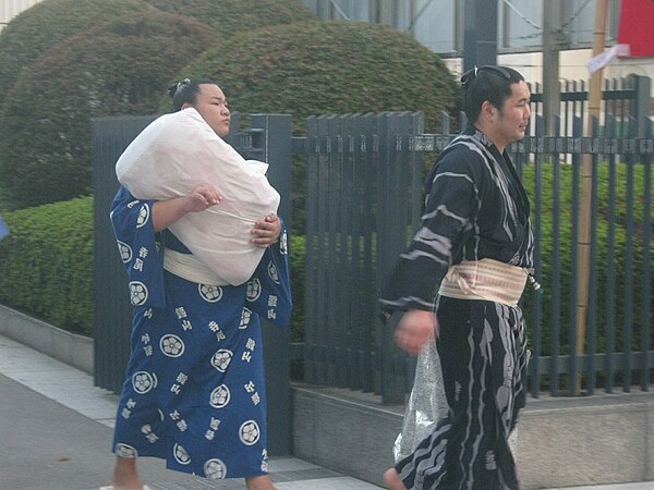 Low-ranking wrestlers carrying a sekitori's belongings (Ryōgoku Kokugikan entrance in 2009)