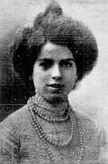 A young Italian woman wearing a high-necked lace blouse and a long string of beads or pearls.