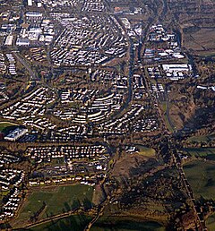 Greenfaulds from the air photographed from above Condorrat. The rugby club is at the bottom with Greenfaulds High School on the right. The view is up the railway line with the Town Centre in the background. Carbrain is above Greenfaulds with Lenziemill to the right.