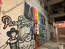 Mural on an alley wall with a mix of black and white figures, rainbow figures, and text saying 'LGBT' and '#remember the past'