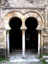 Mossàrab: porta geminada d'arc de ferradura amb capitells vegetals i arrabà delimitant l'arcuació. Santiago de Peñalba de Santiago (el Bierzo)