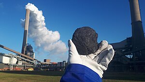 Piece of coal in front of a coal firing power plant.jpg