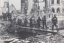 Men of the 6th Airborne Division crossing the remnants of the final bridge at Pont L'Eveque on 24 August. The devastation caused during the two-day battle, particularly due to the fires, is plain to see. Pont LEveque Bridge August 1944.jpg