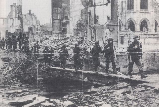 Men of the 6th Airborne Division crossing the remnants of the final bridge at Pont L'Eveque on 24 August. The devastation caused during the two-day ba