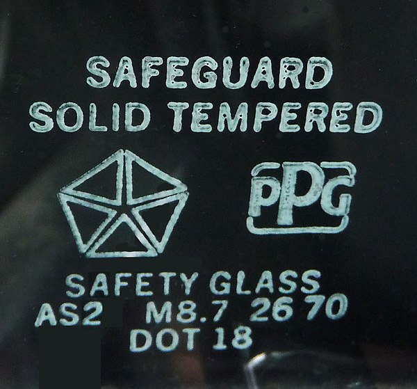 Safety approval markings on an automobile vent window made for a Chrysler car by PPG.