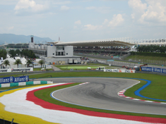 Pista de asfalto de Fórmula 1 em uma chicane, com uma arquibancada ao fundo