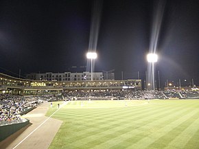 A green baseball field and its grandstand at night