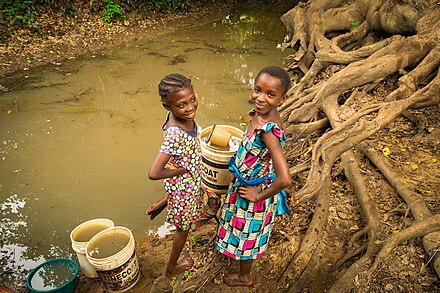Children fetch water from a muddy stream in a rural area during dry season. The water is taken back home and undergoes filtration and other treatments before usage.