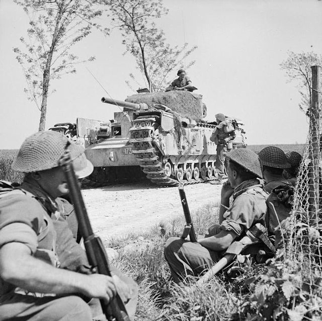A Churchill tank halts near infantry of 1st Battalion, London Irish Rifles, of 167th Brigade of 56th Division, near Tanara, Italy, April 1945.