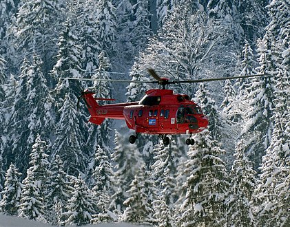 Helicopter above forest Hubschrauber bläst Schnee ab.