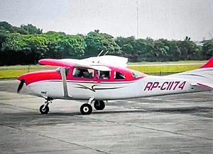 A Cessna 206 with a red and white livery on a tarmac.